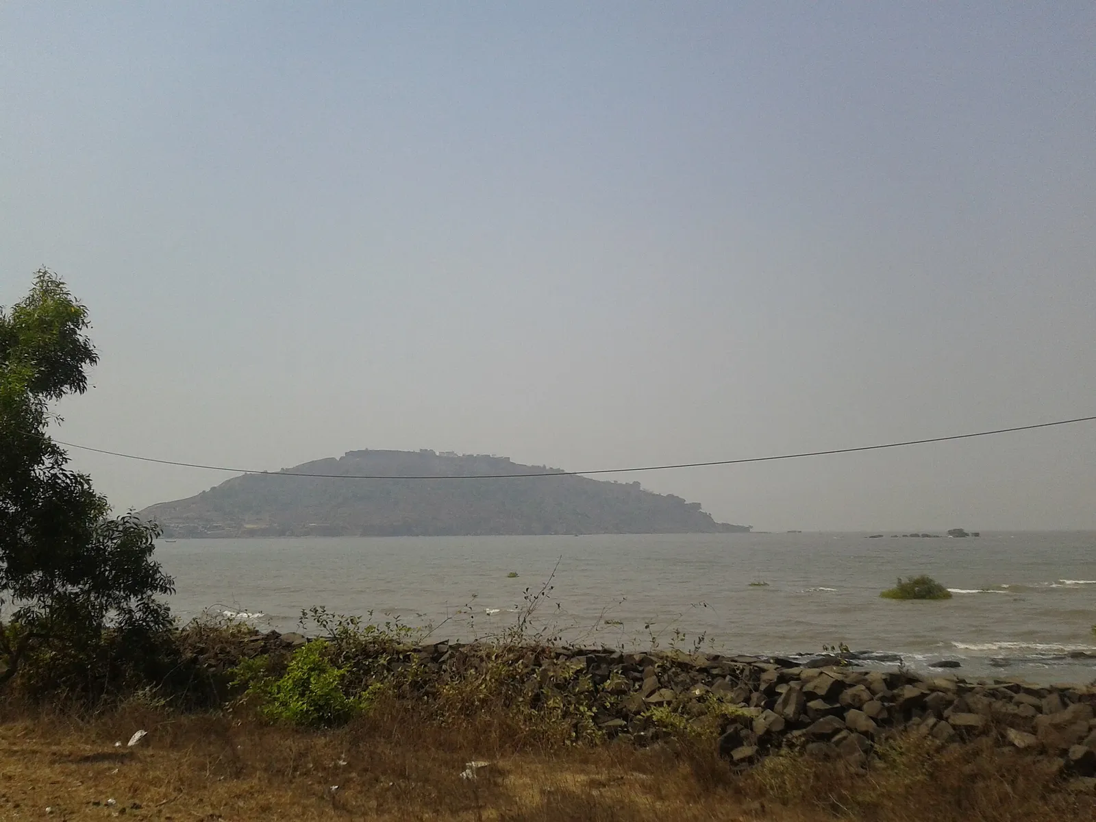 The sands of Kashid beach south of Alibag, with a wooded headland