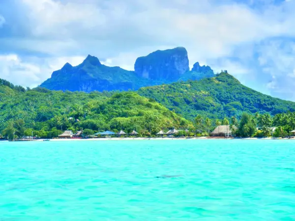 Panoramic view of Bora Bora’s lagoon dotted with overwater bungalows against a blue sky