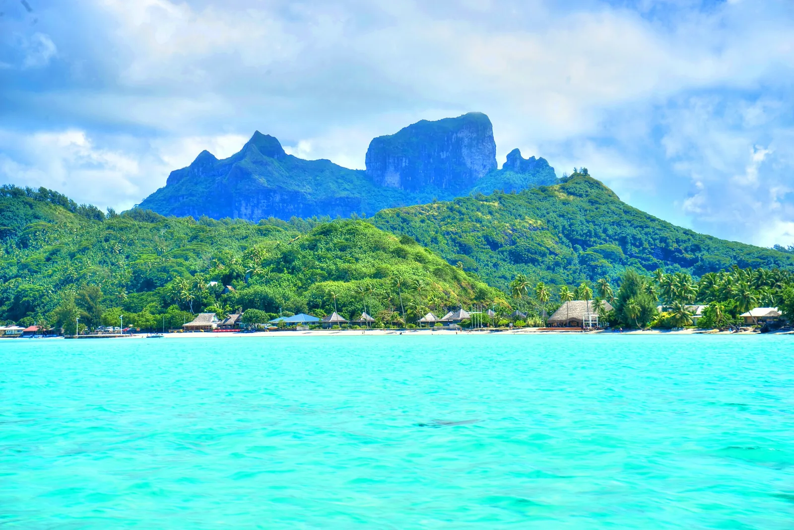 Panoramic view of Bora Bora’s lagoon dotted with overwater bungalows against a blue sky