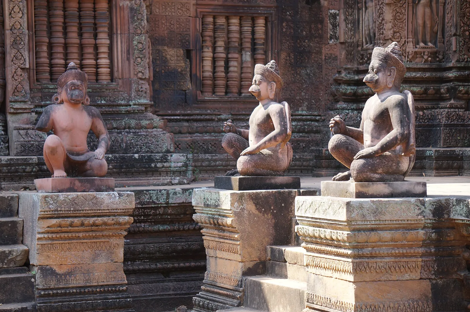 Carved guardian statues in front of the red sandstone shrines of Banteay Srei