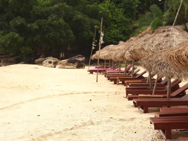 Sun loungers and thatched umbrellas on a beach in Sihanoukville