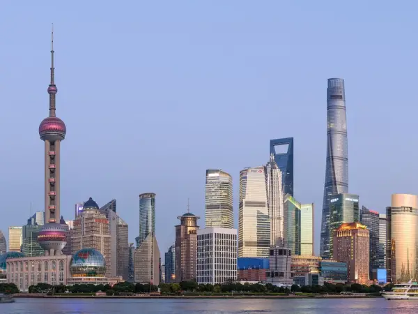 Panoramic view of Shanghai's Pudong skyline, showing skyscrapers, Huangpu River and distant hills.
