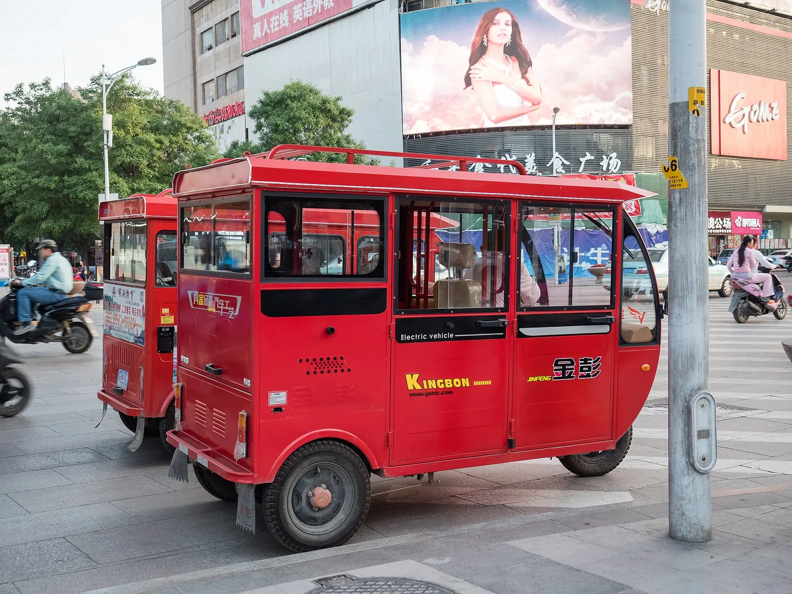 Small yellow taxi parked on a street in Jinan, with city buildings and traffic signs nearby.
