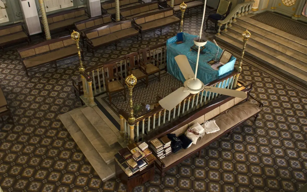 Inside Keneseth Eliyahoo Synagogue: wooden pews, vaulted ceiling, and historic plaques