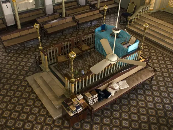 Inside Keneseth Eliyahoo Synagogue: wooden pews, vaulted ceiling, and historic plaques