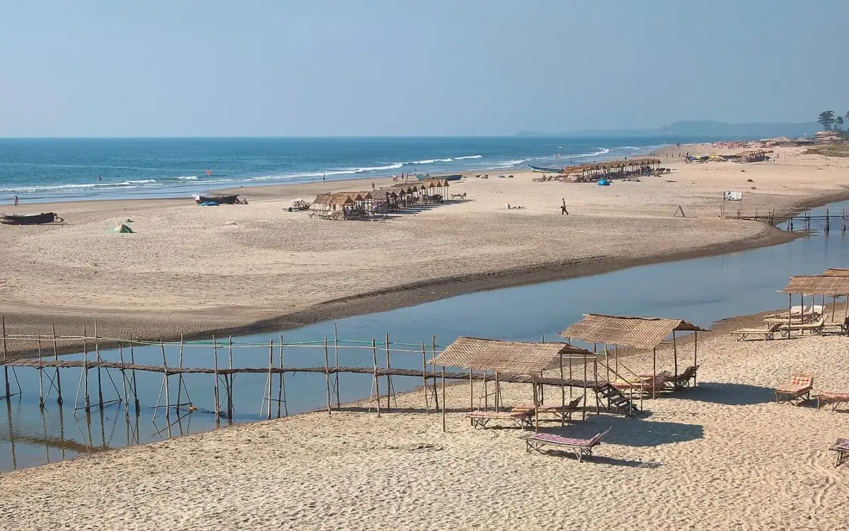 Quiet Mandrem Beach with white sand, clear water and the Mandrem River mouth in the background