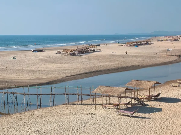 Quiet Mandrem Beach with white sand, clear water and the Mandrem River mouth in the background