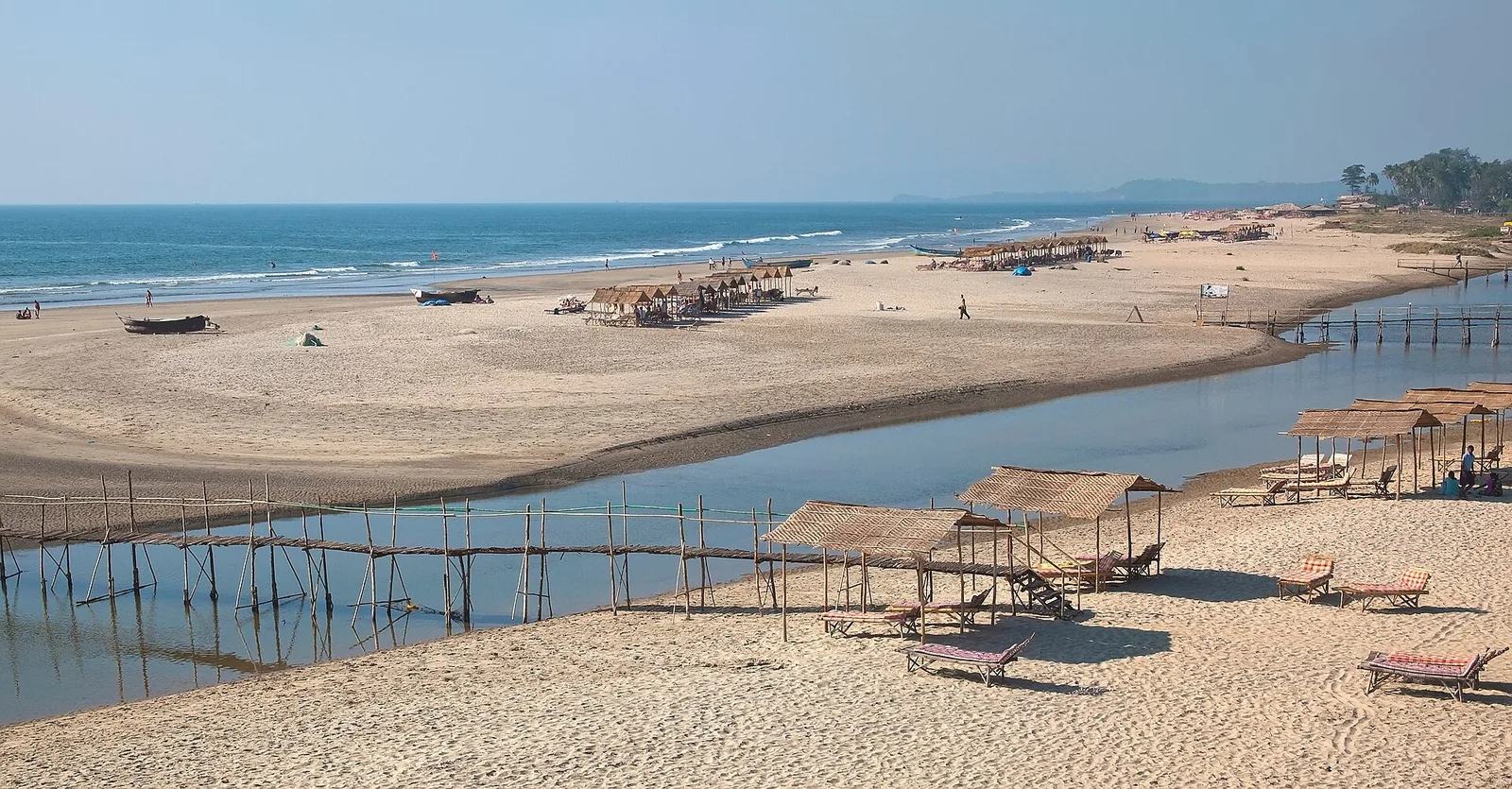 Quiet Mandrem Beach with white sand, clear water and the Mandrem River mouth in the background