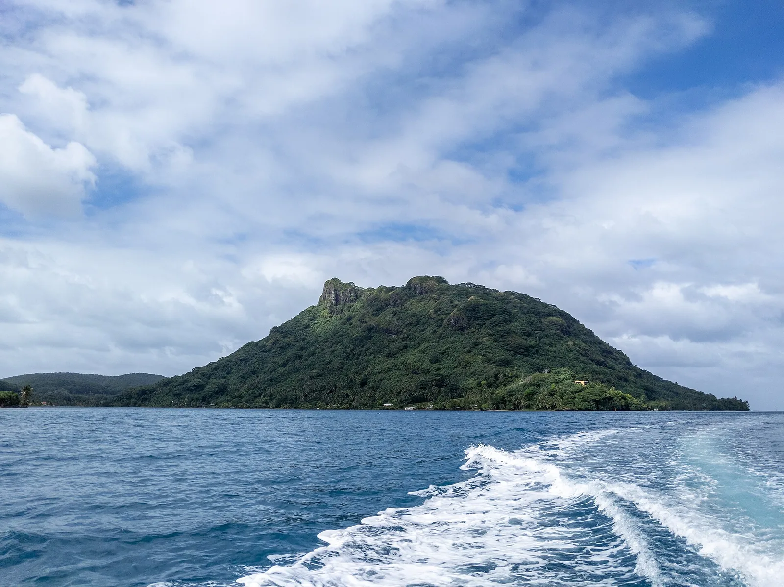 A forested peak on Huahine seen from a boat on the lagoon