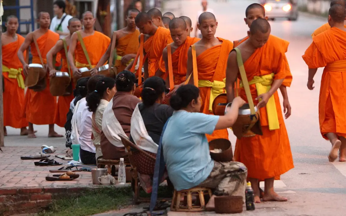 Monks in saffron robes collecting alms at dawn in Luang Prabang