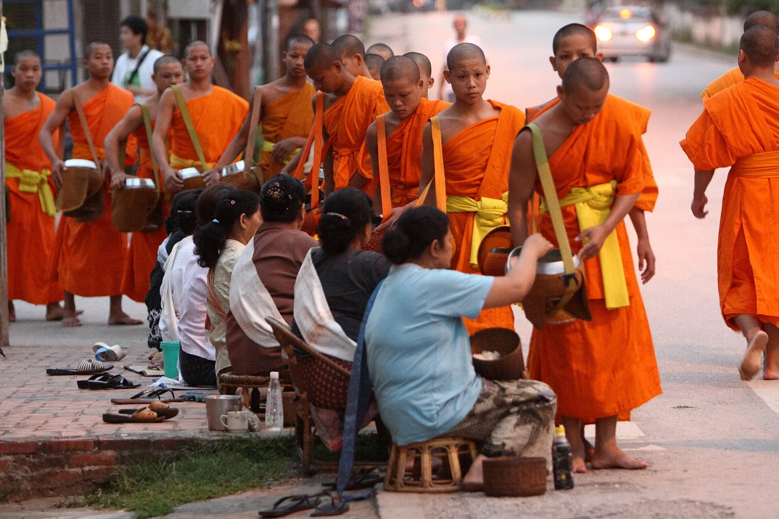 Monks in saffron robes collecting alms at dawn in Luang Prabang