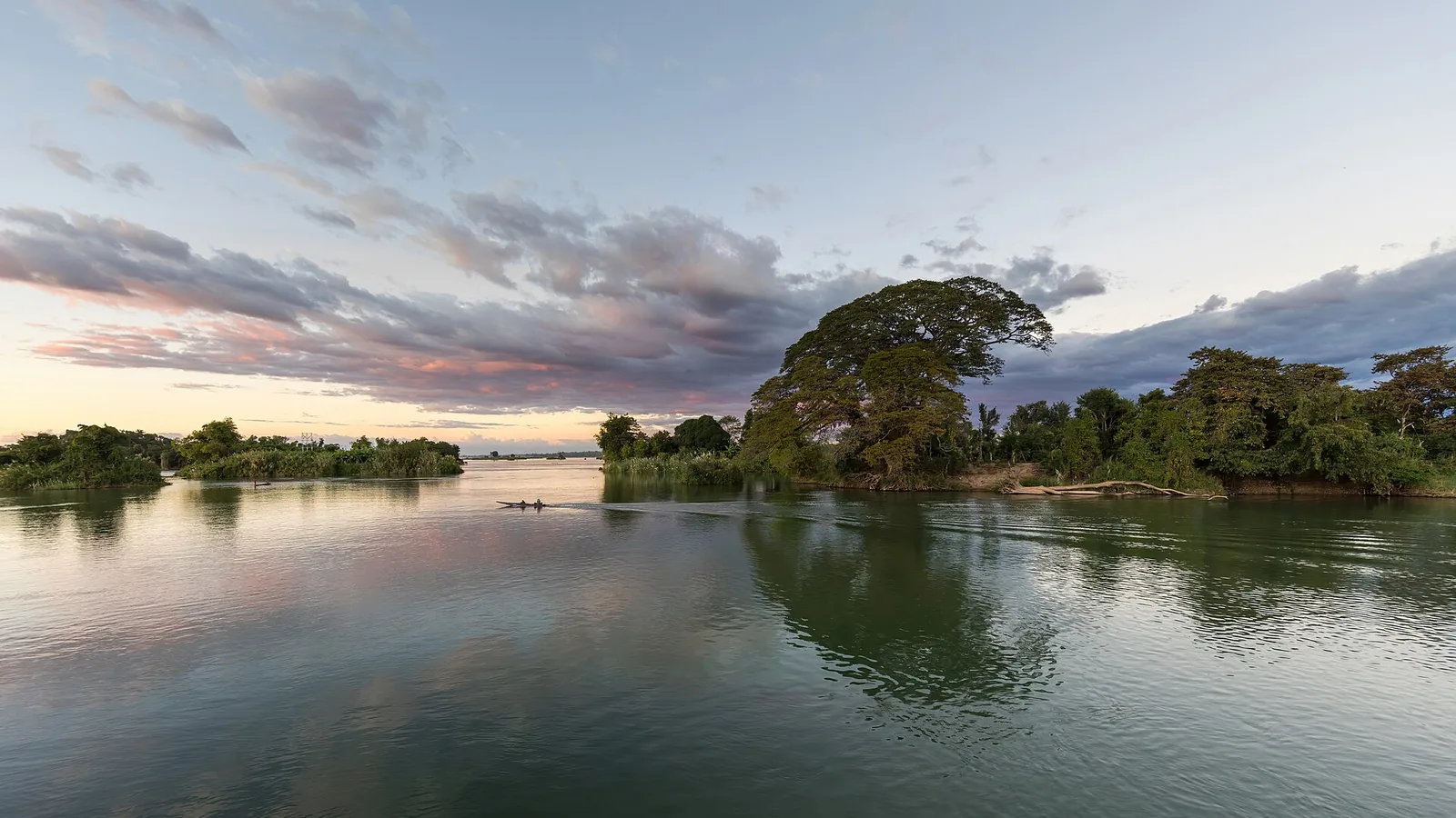 A wooden boat on the Mekong at sunset, seen from Don Det in Si Phan Don