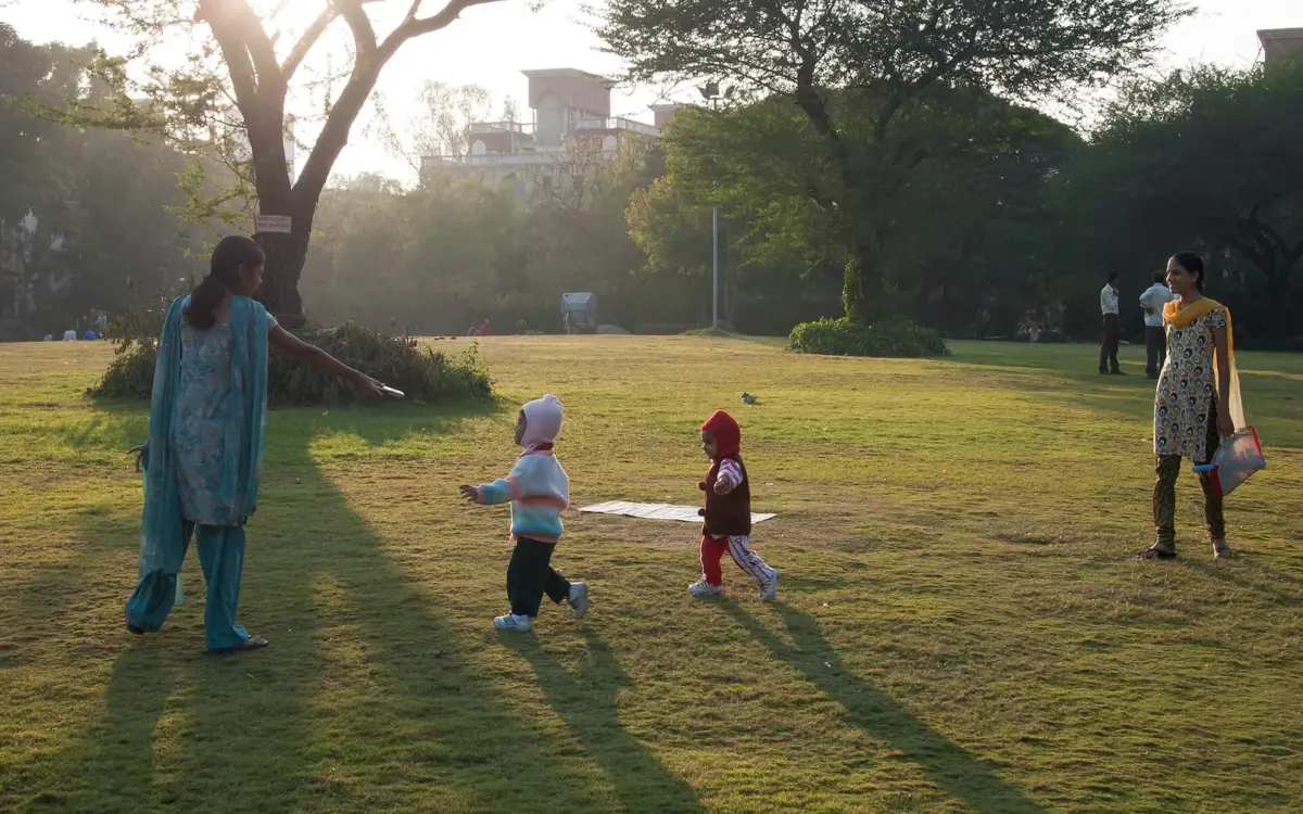 Mothers holding children strolling on a tree‑lined street in Pune, showcasing everyday life in the city