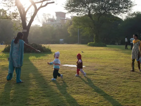 Mothers holding children strolling on a tree‑lined street in Pune, showcasing everyday life in the city
