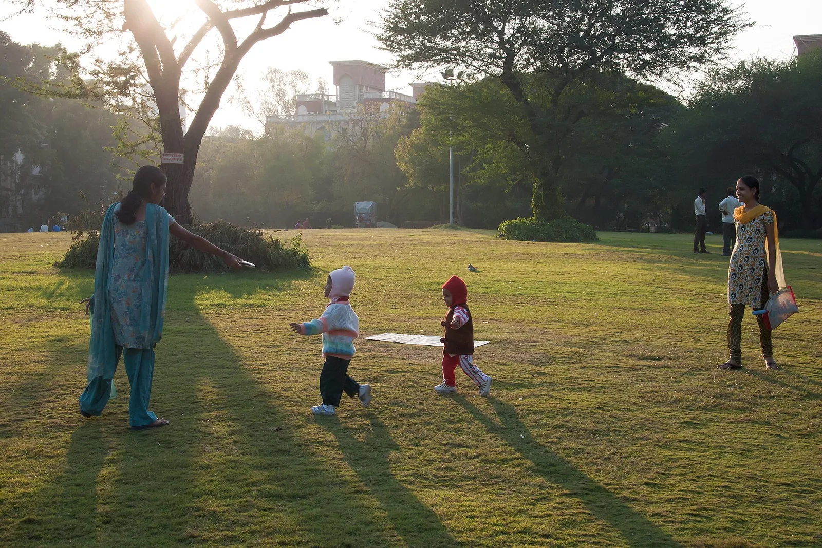 Mothers holding children strolling on a tree‑lined street in Pune, showcasing everyday life in the city