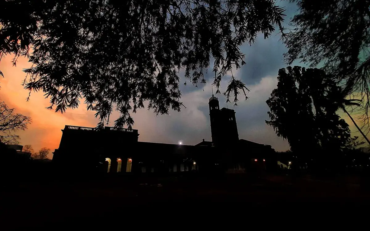 Open quadrangle with students walking past stone arches and green lawns at the university