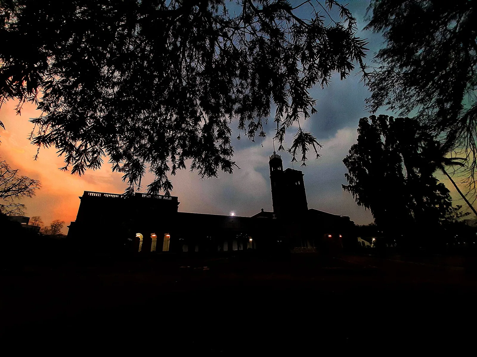 Open quadrangle with students walking past stone arches and green lawns at the university