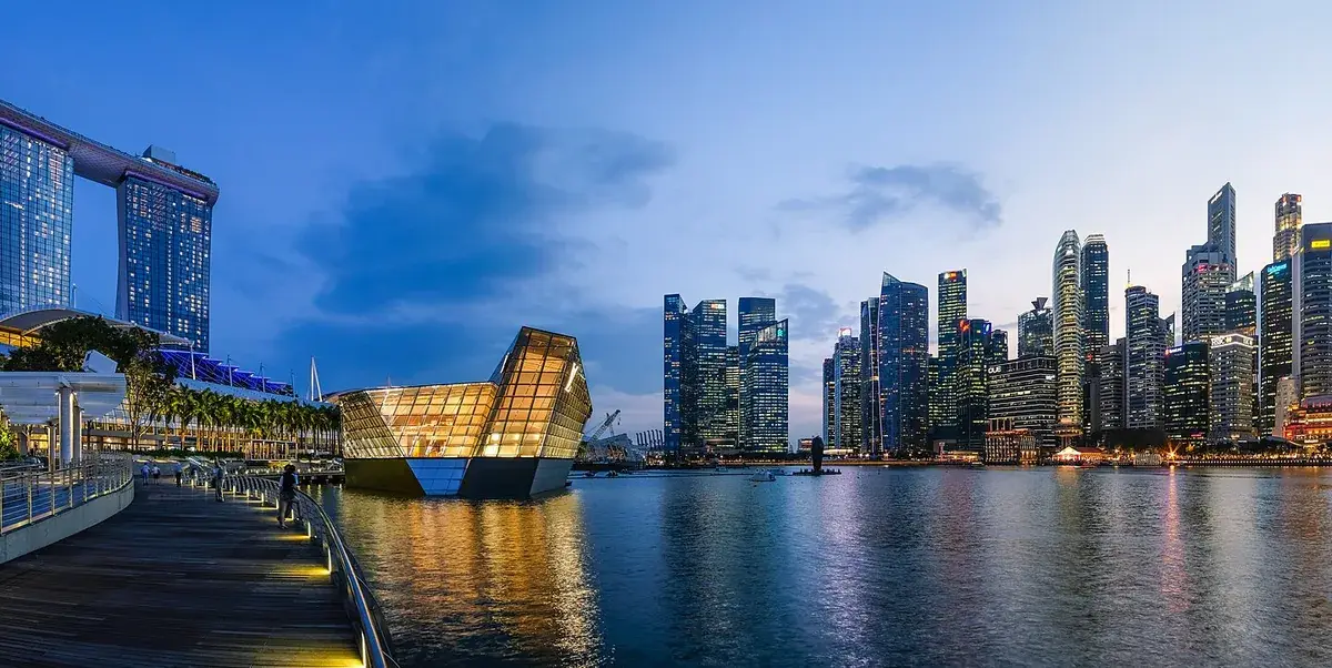 Marina Bay at dusk 2018 with Marina Bay Sands hotel, a glass Louis Vuitton storefront and the illuminated CBD skyline