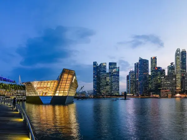 Marina Bay at dusk 2018 with Marina Bay Sands hotel, a glass Louis Vuitton storefront and the illuminated CBD skyline