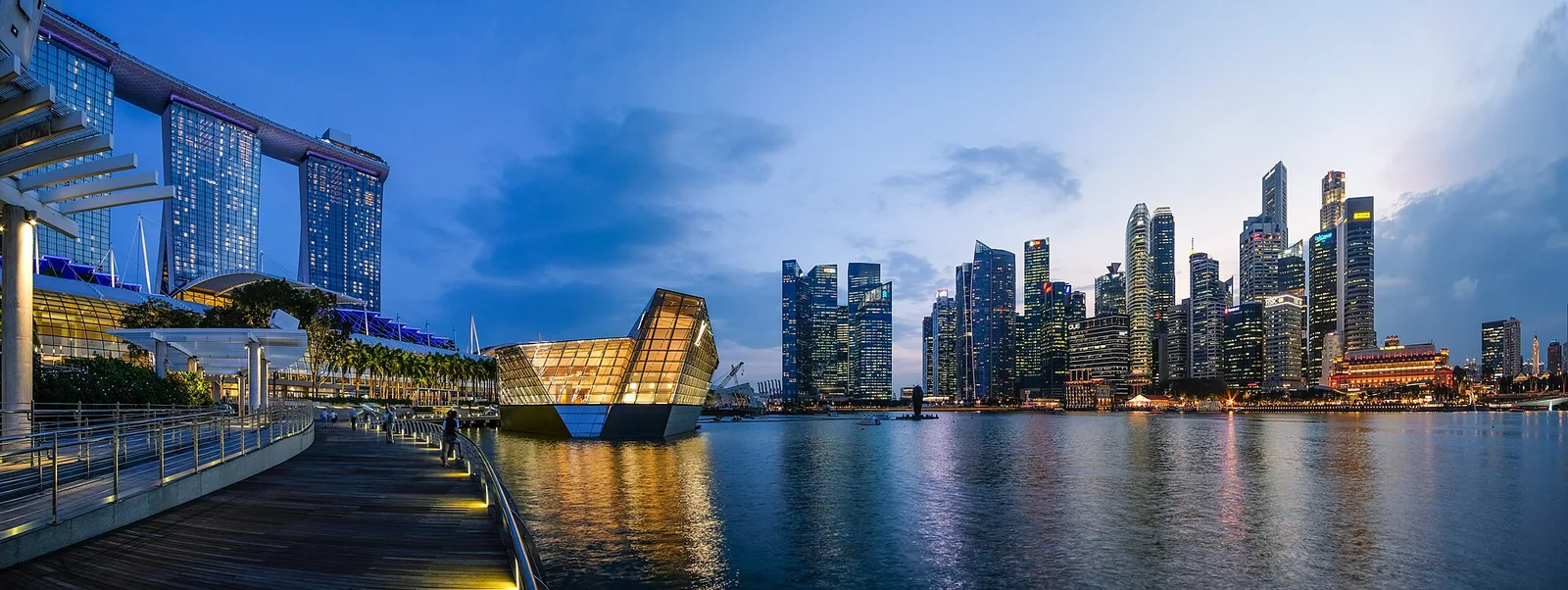 Marina Bay at dusk 2018 with Marina Bay Sands hotel, a glass Louis Vuitton storefront and the illuminated CBD skyline