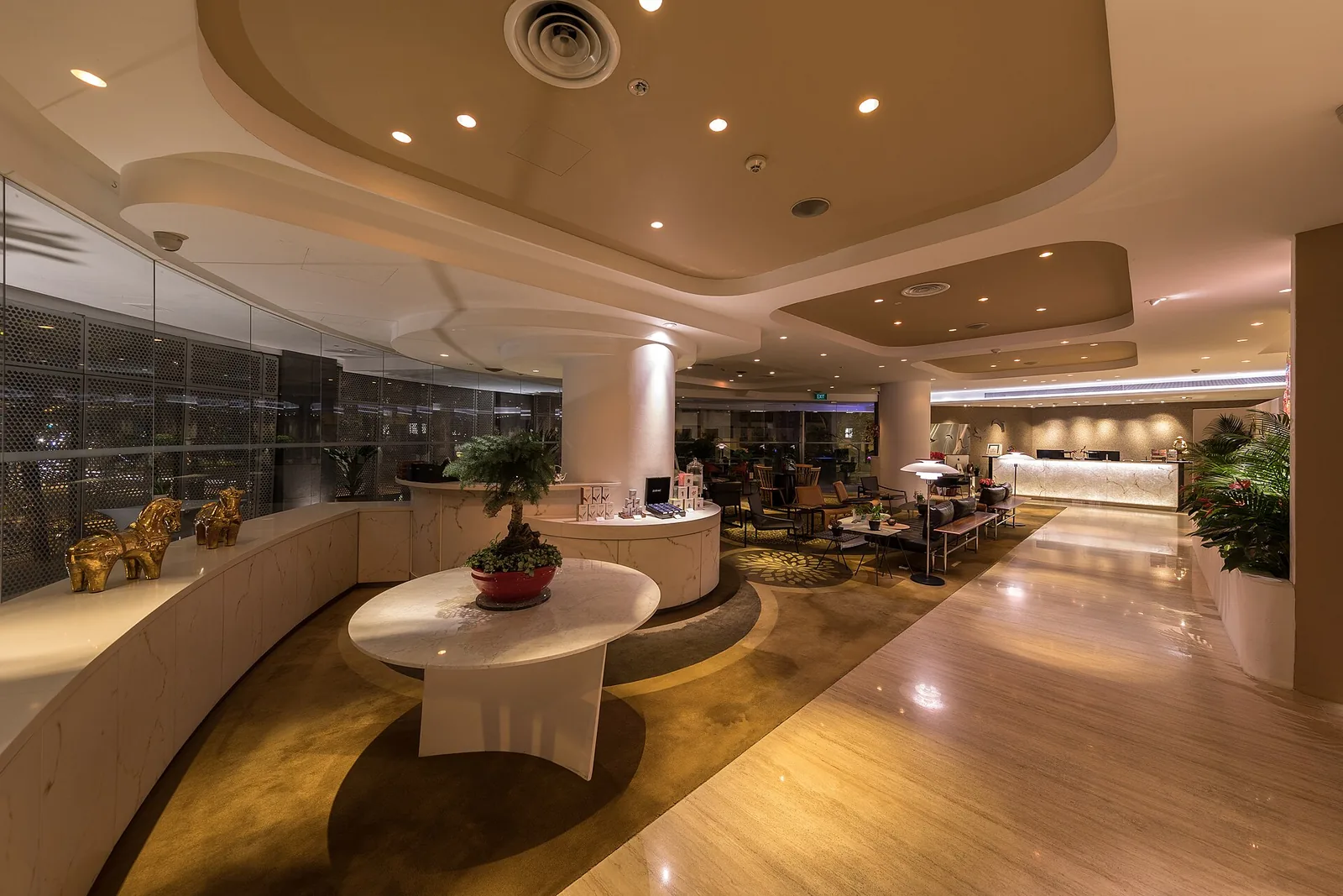 Wangz Hotel lounge interior featuring polished parquet floor, curved walls, decorative pillars, ceiling details and a round…