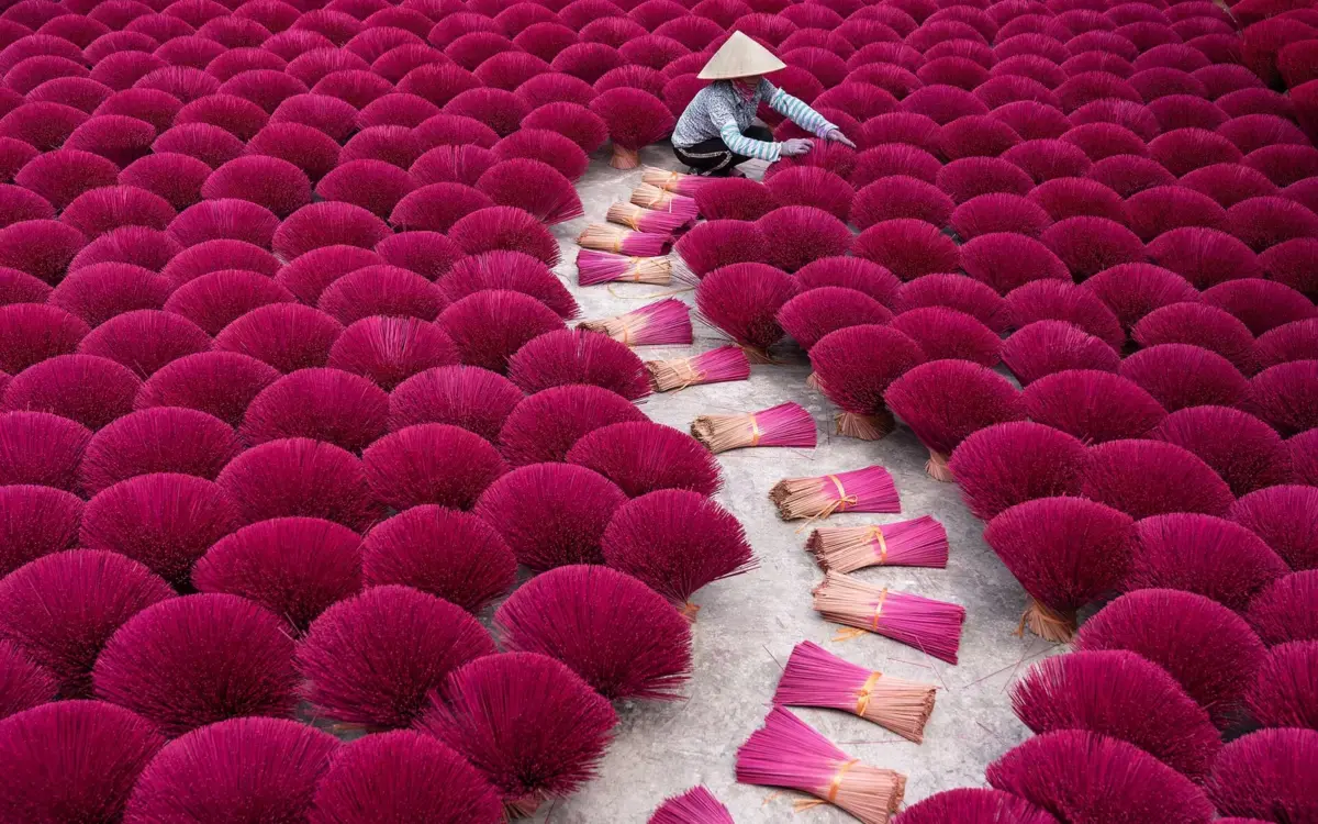 Incense sticks arranged on a low tray, thin smoke curling up, in Quang Phu Cau village outskirts of Hanoi.